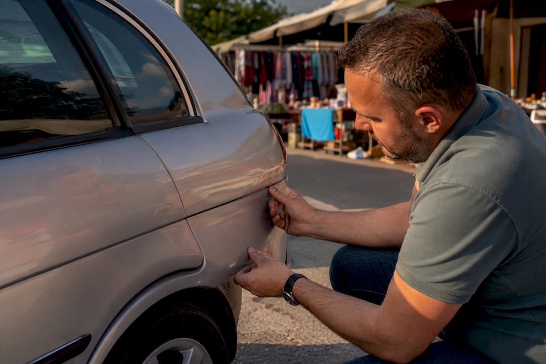 Mani che indicano la vernice dell'auto irregolare e le fessure dei pannelli