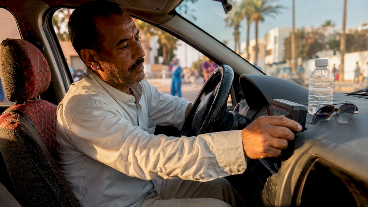 Moroccan taxi driver checking fare meter inside car
