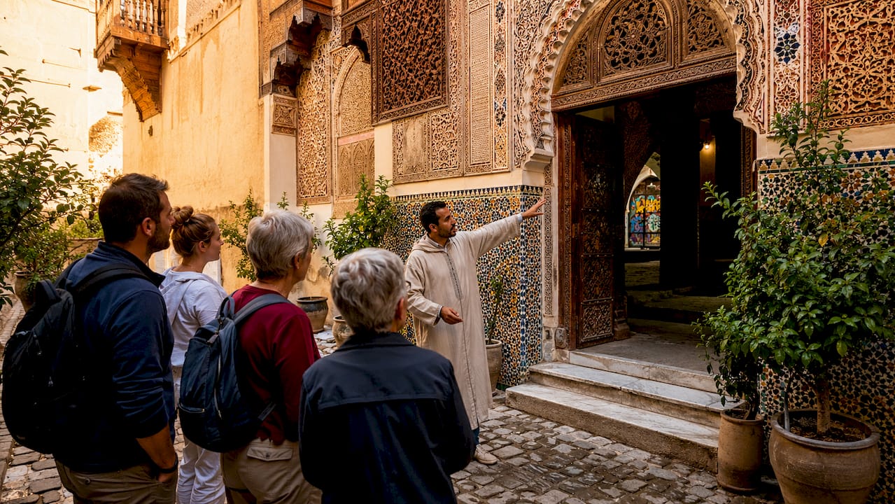 Fez Tours: Your Complete Cultural Travel Guide 2 Group observing Fez madrasa architectural details