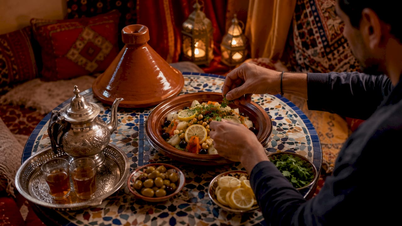 Hands preparing traditional Moroccan tagine inside desert camp