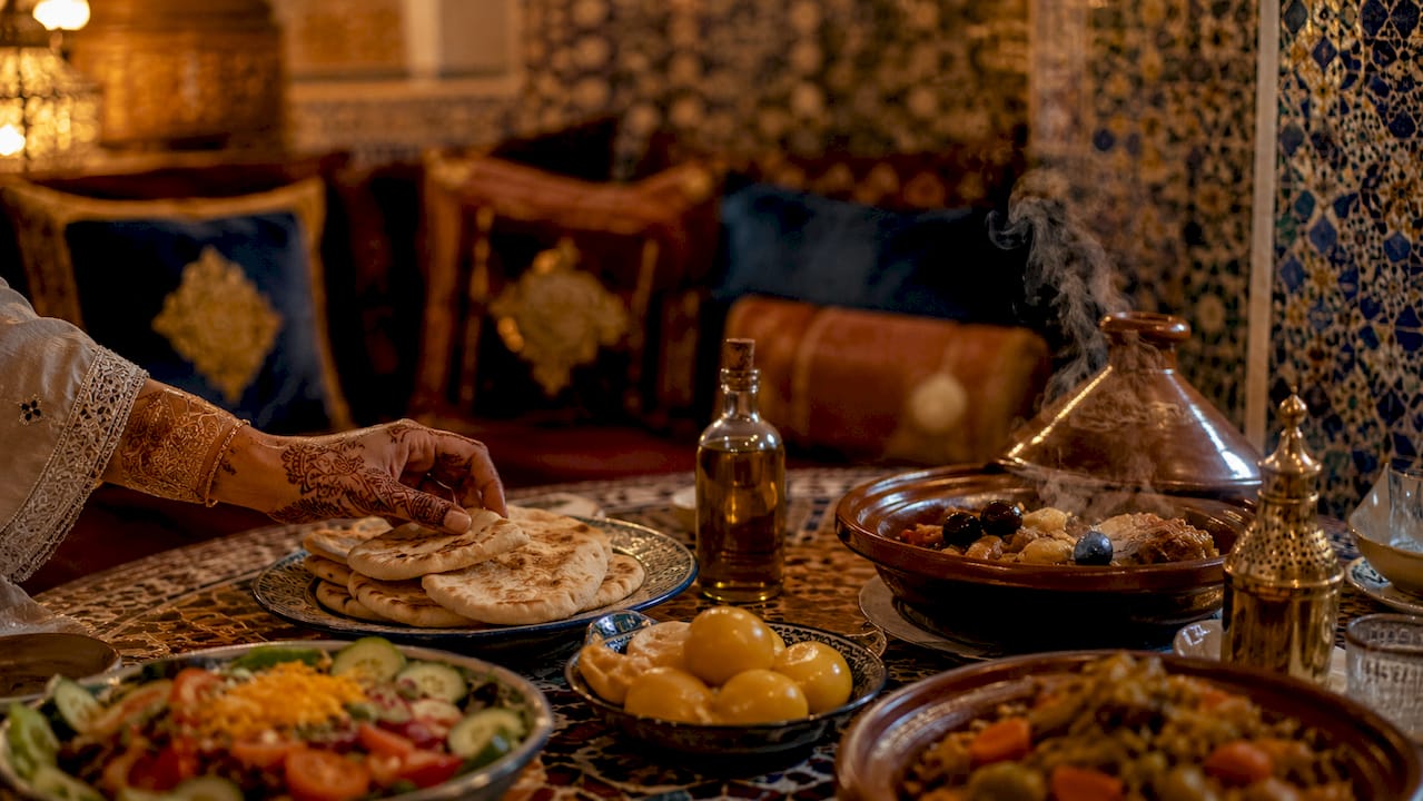 Morocco Tours From South Africa: Travel Guide 2 Traditional Moroccan dishes and hands dining outdoors