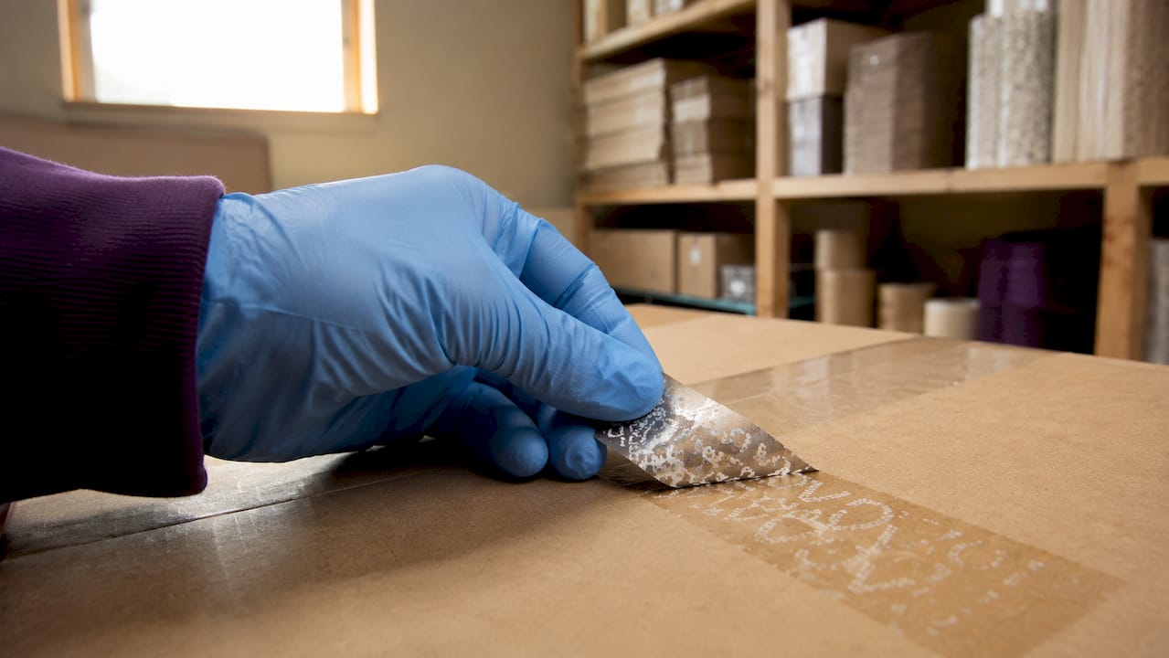 Close-up of glove peeling destructible security label