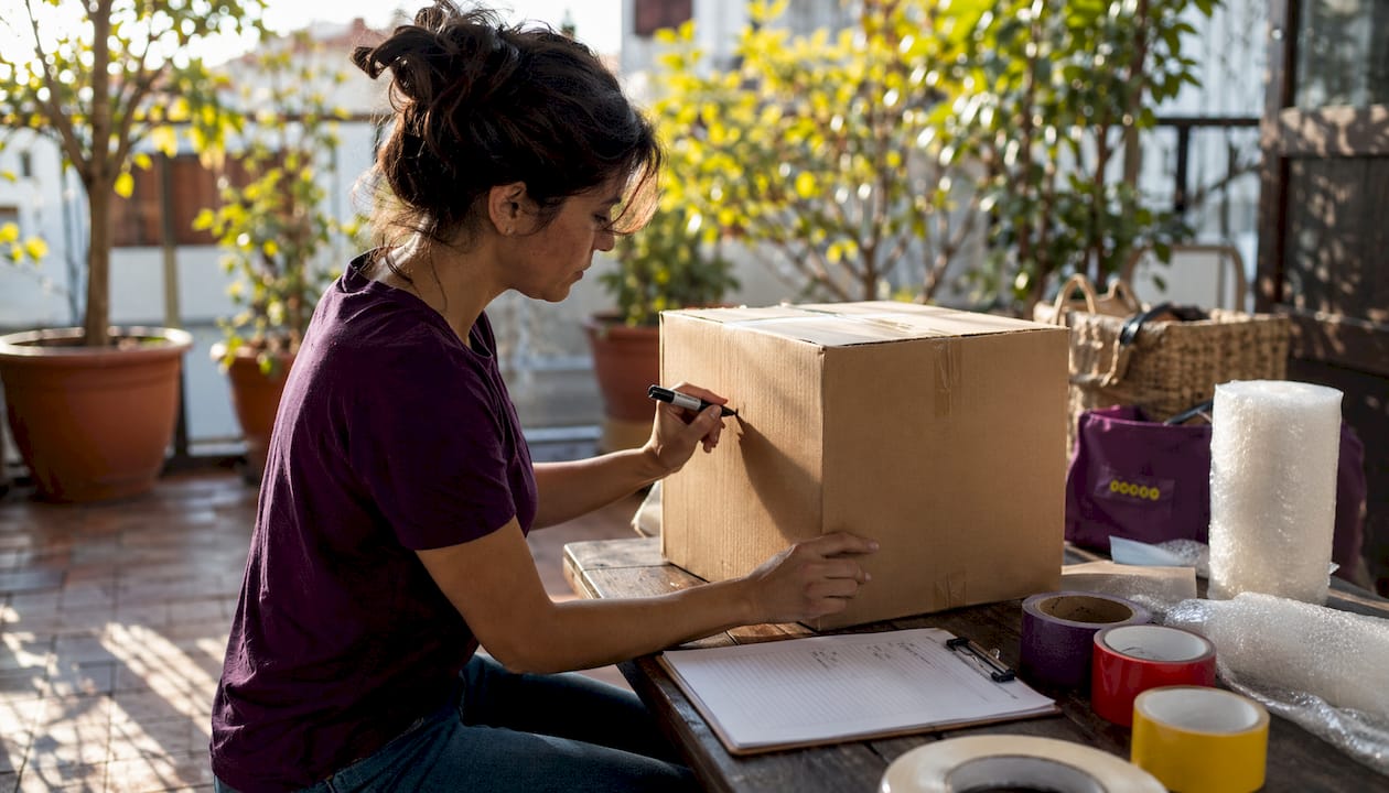 Hands labeling moving box with checklist