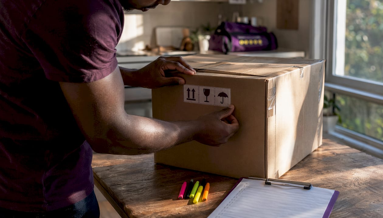 Hands writing detailed labels on moving box sides