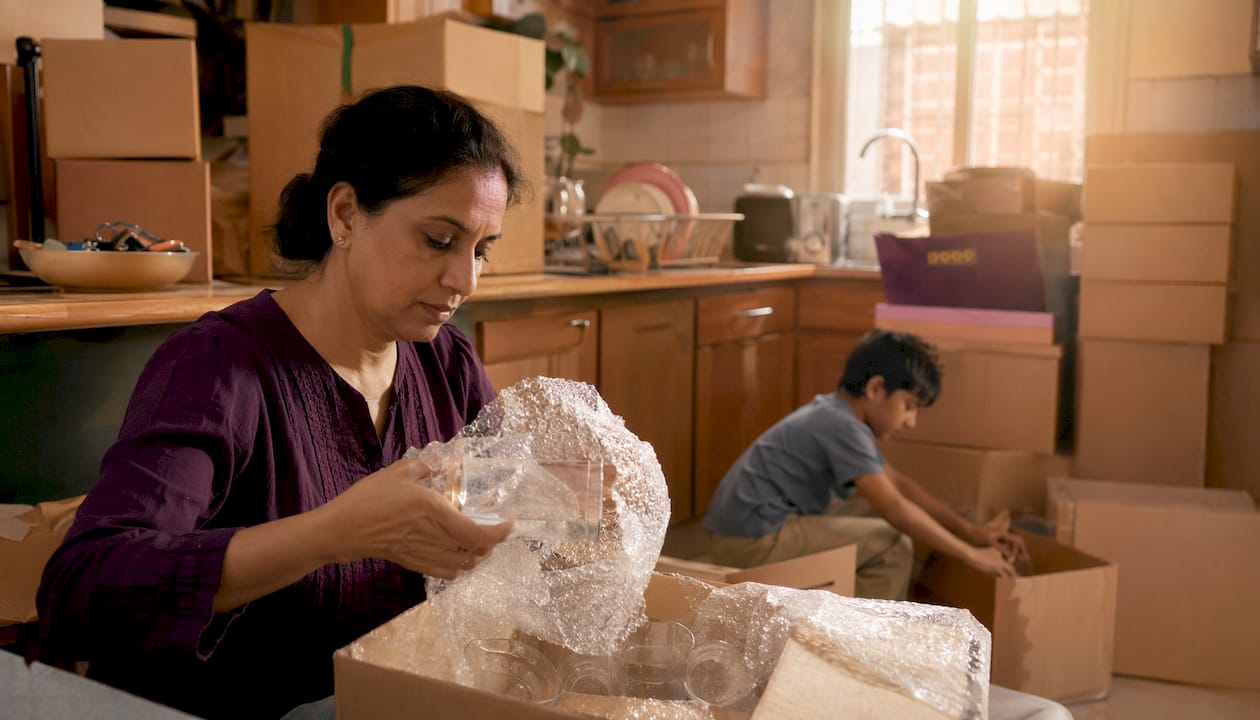 Woman packing fragile glassware in living room