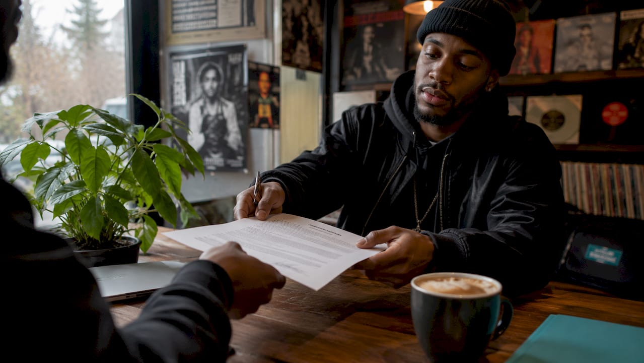 Hands exchanging signed contract at urban office table