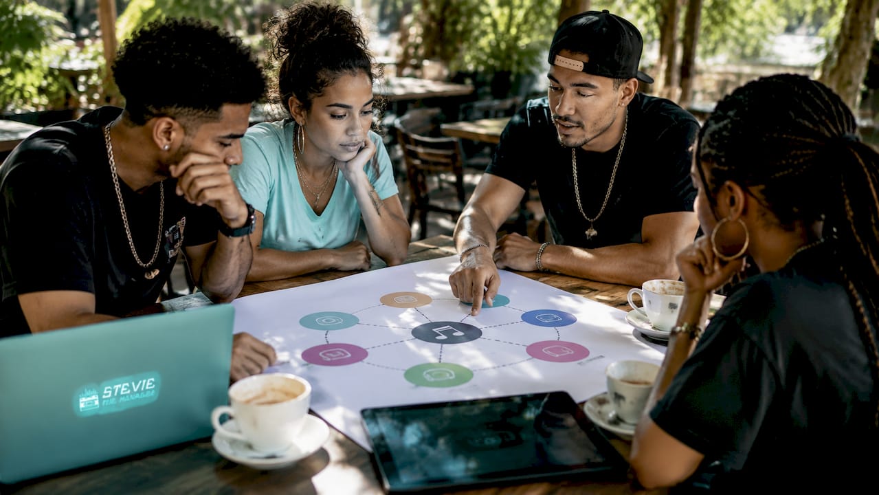 Team discussing music promotion channels over table