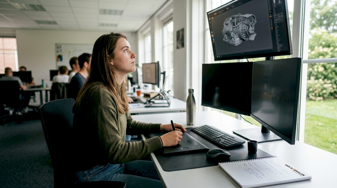 Een vrouw werkt op kantoor aan 3D-modellen achter haar werkstation.