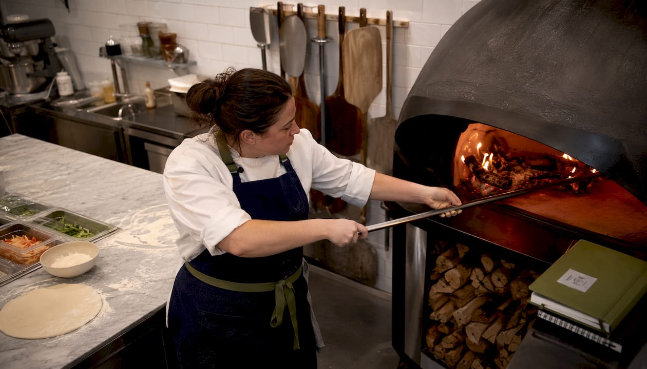 Chef tending commercial wood fired pizza oven