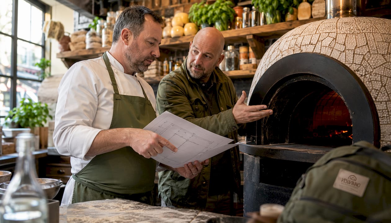 Kitchen manager consulting with technician by pizza oven