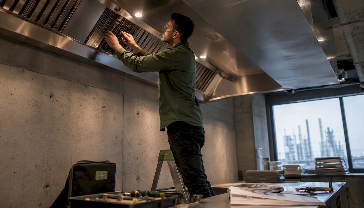 Technician installing commercial kitchen Type 1 hood