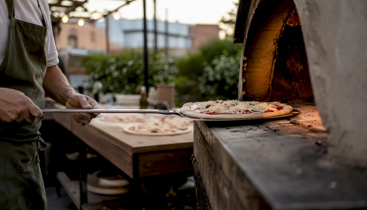 Cocinero de pizza cargando pizza en el horno