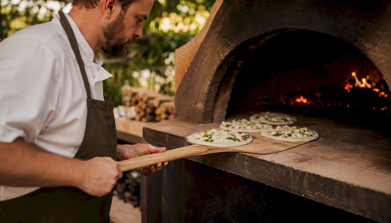 Chef loading pizzas into professional oven