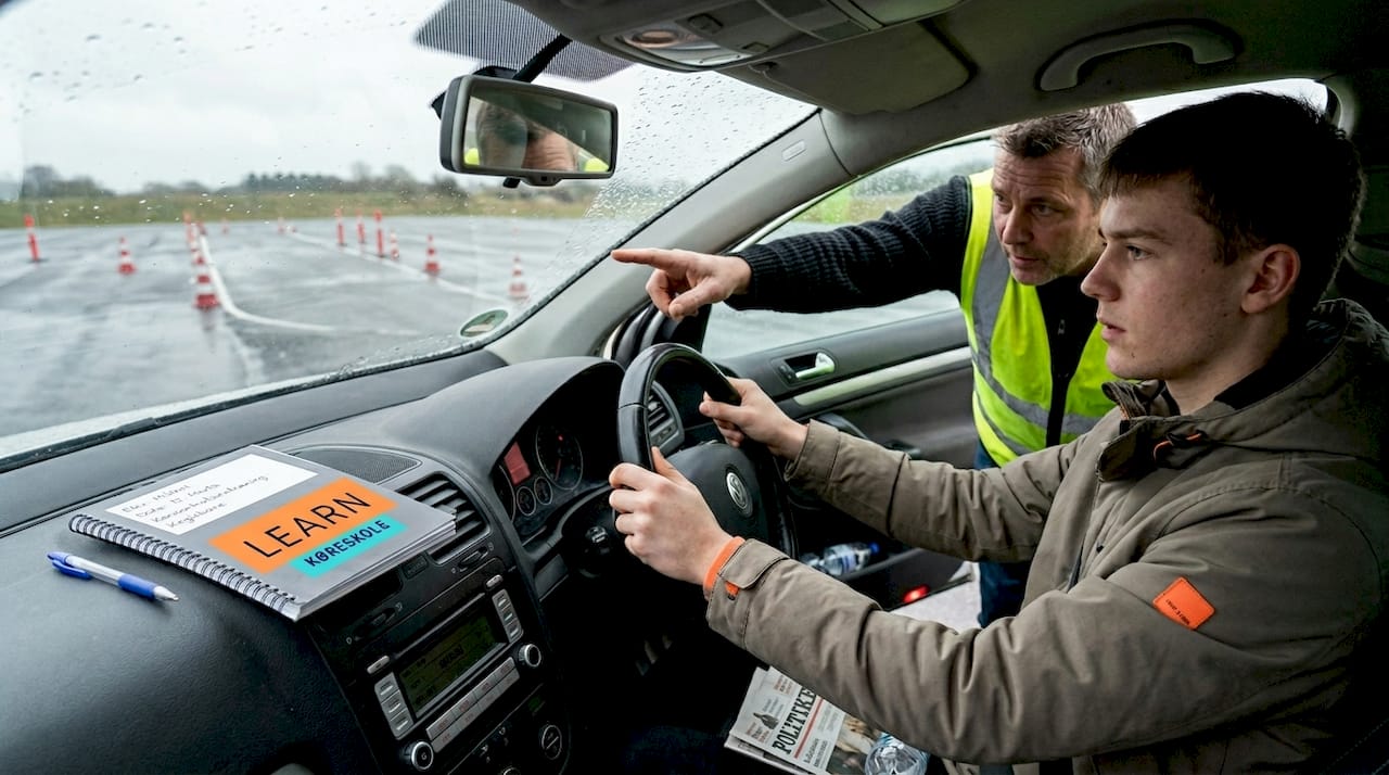 En elev træner køreteknik sammen med sin kørelærer ved bilen.