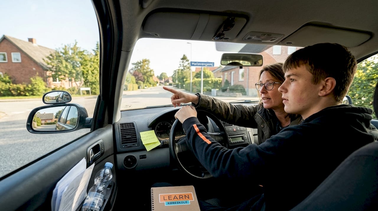 En elev er ude at køre med sin kørelærer i skolevognen for at træne bilkørsel.