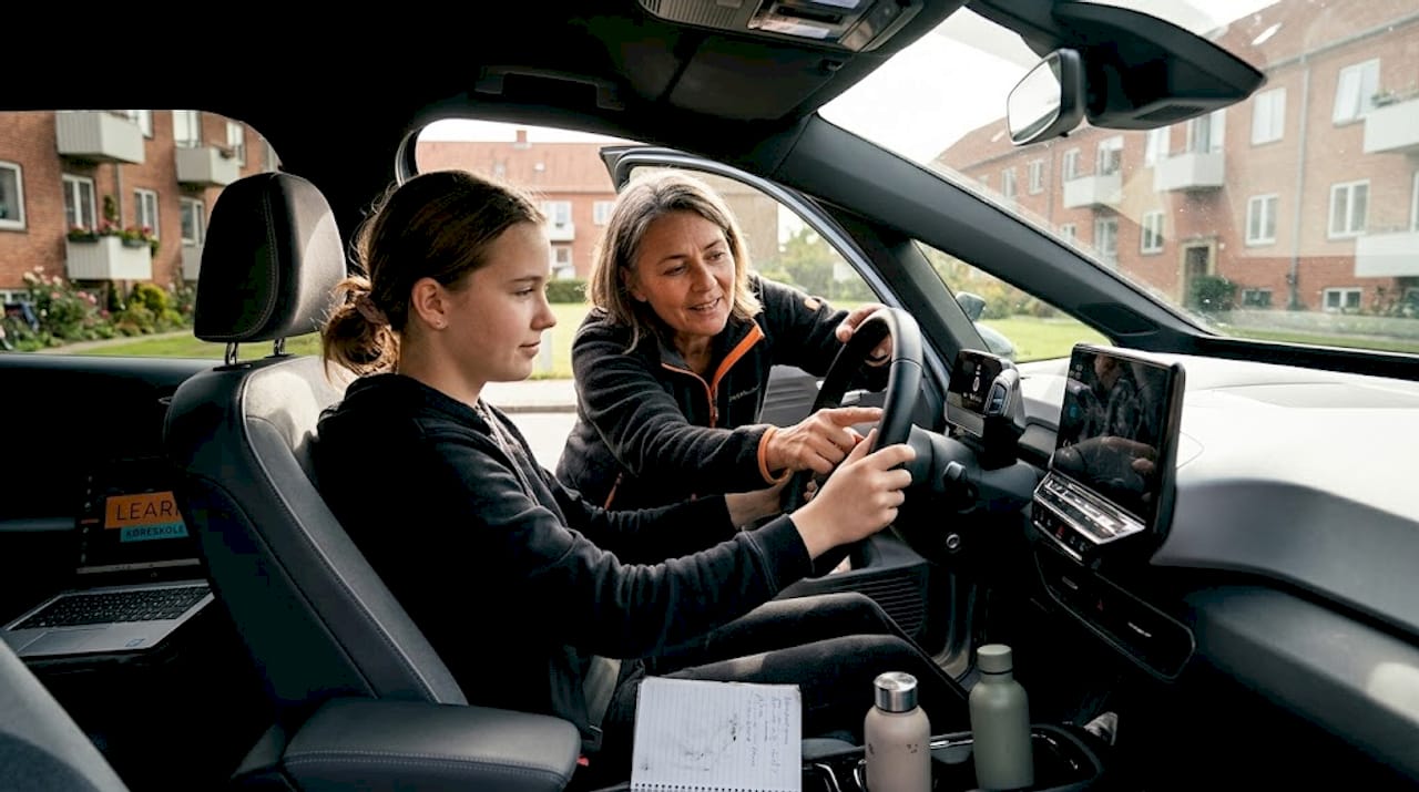 En underviser gennemgår elbilens grundlæggende funktioner med en elev