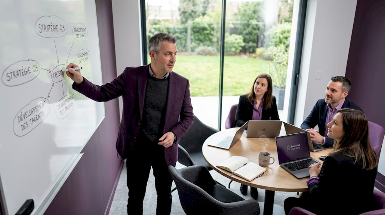 Le manager expose les objectifs de l’équipe au tableau lors d’une réunion.