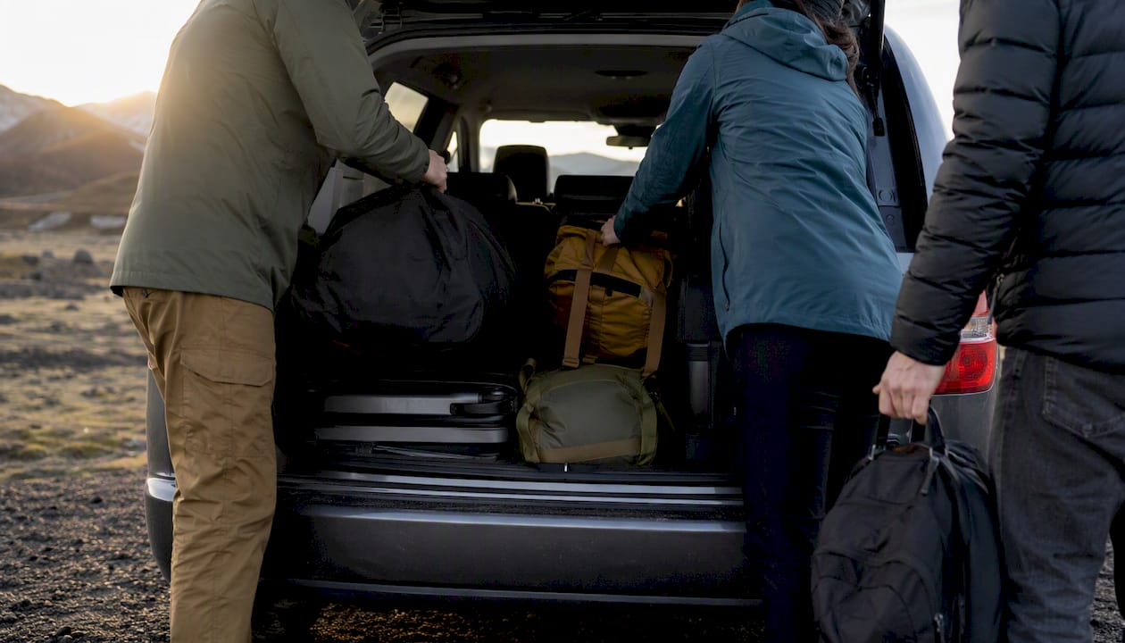 Travelers loading luggage into minivan trunk