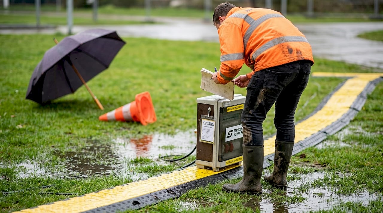 De veiligheidsadviseur controleert de tijdelijke elektriciteitsvoorziening op het grasveld.
