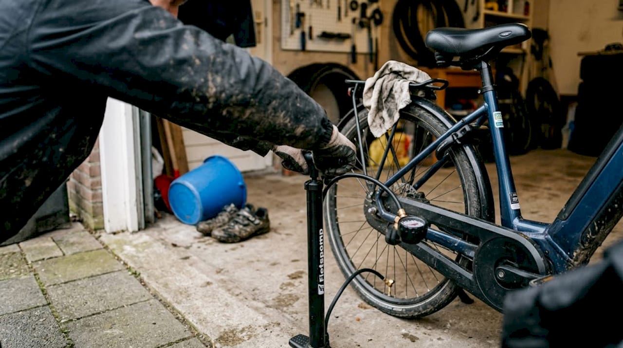 Een vrouw is haar e-bikebanden aan het oppompen in de garage.