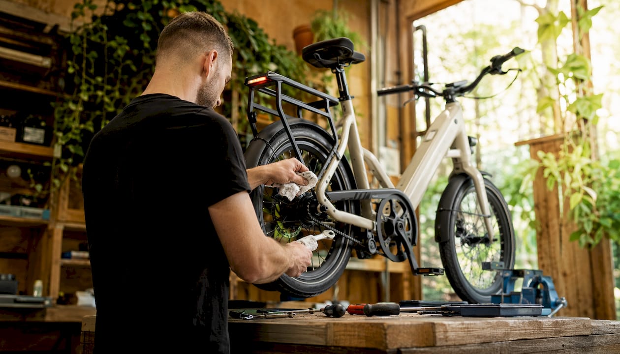 Een monteur is bezig met het onderhoud van een compacte elektrische fiets.