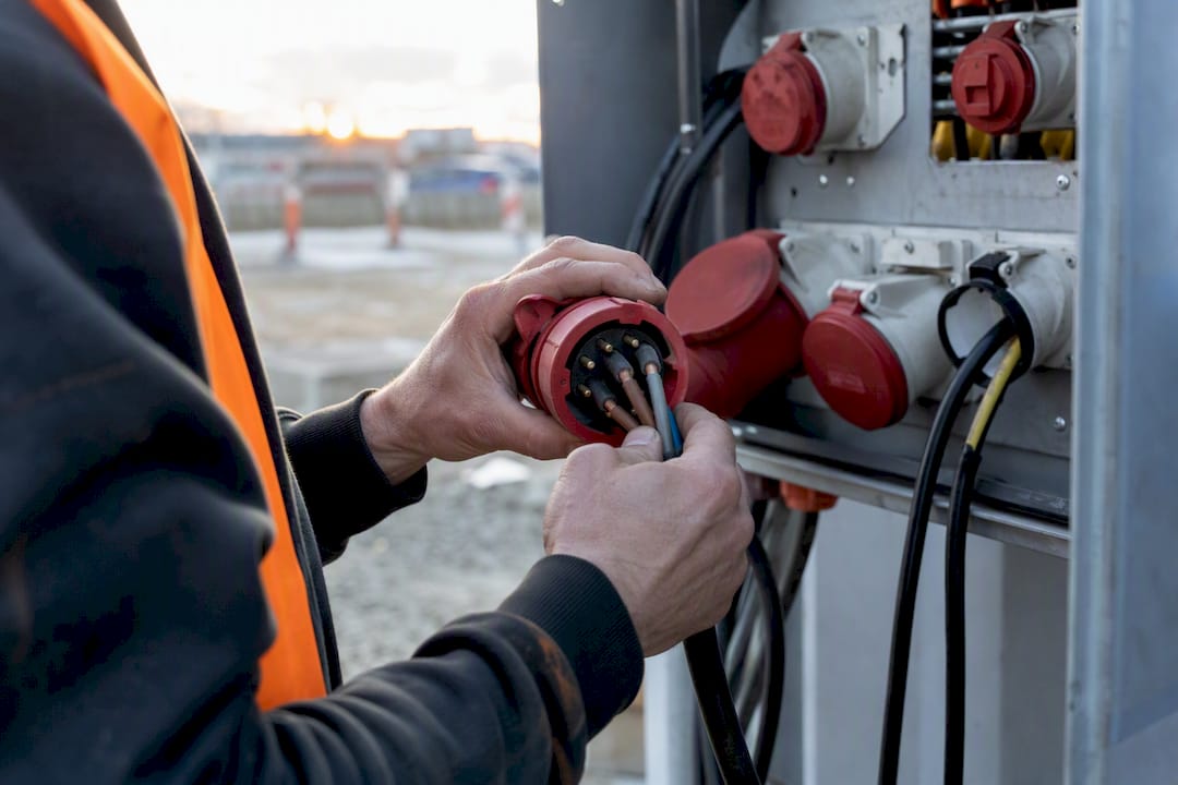 Handen die een powerlock-connector bedraden in een verdeelkast