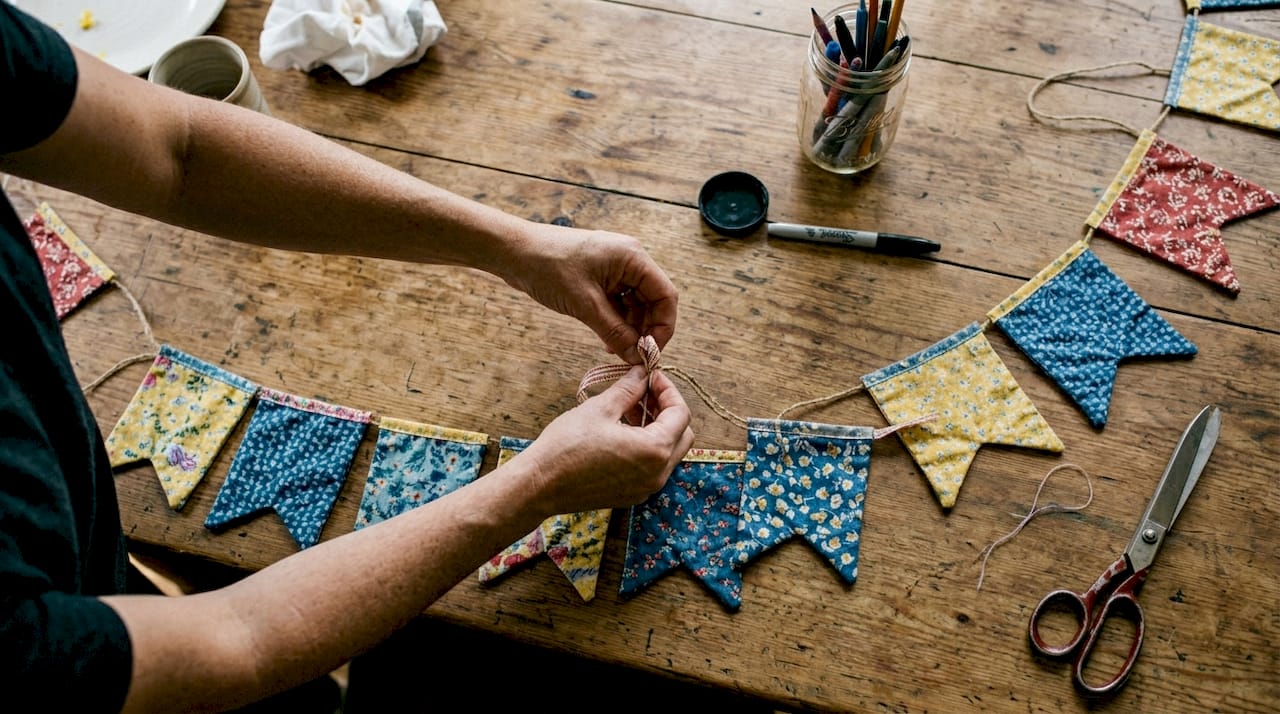 Hands assembling fabric naming banner on table