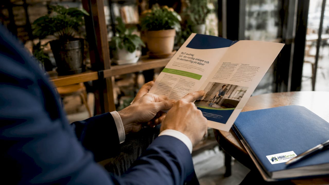 En hand håller upp en broschyr som förklarar RUT-avdraget i detalj.