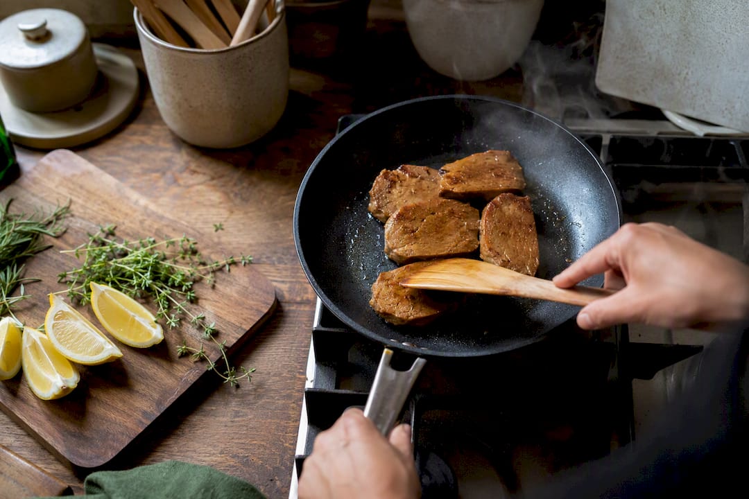 Seitan slices cooking in skillet