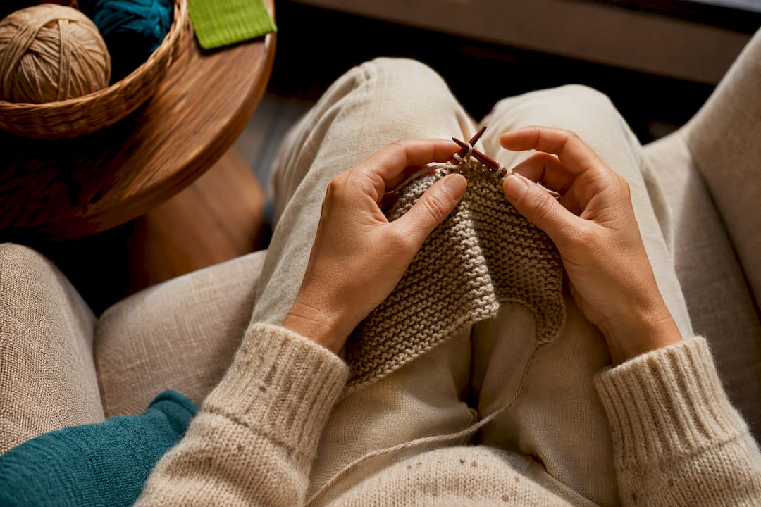 Hands knitting a row at home