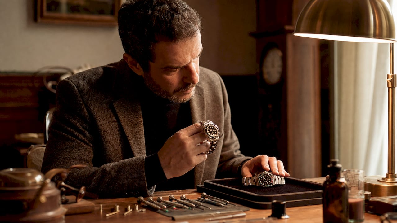 Man inspecting vintage and modern watches at desk