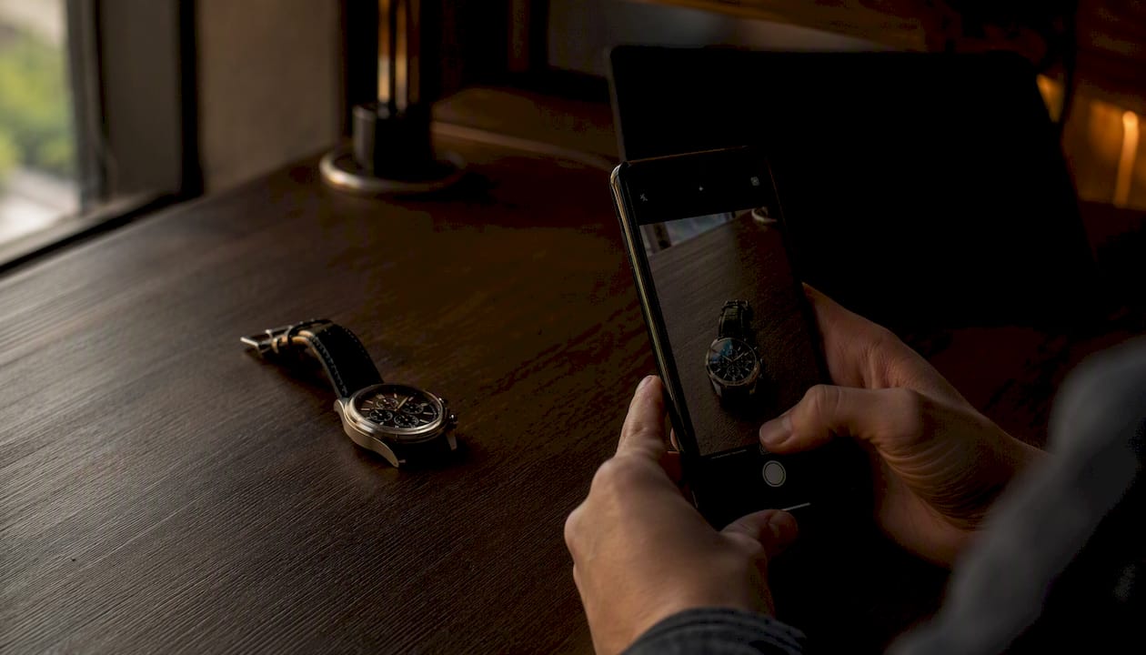 Cartier-style watch next to smartphone for photos