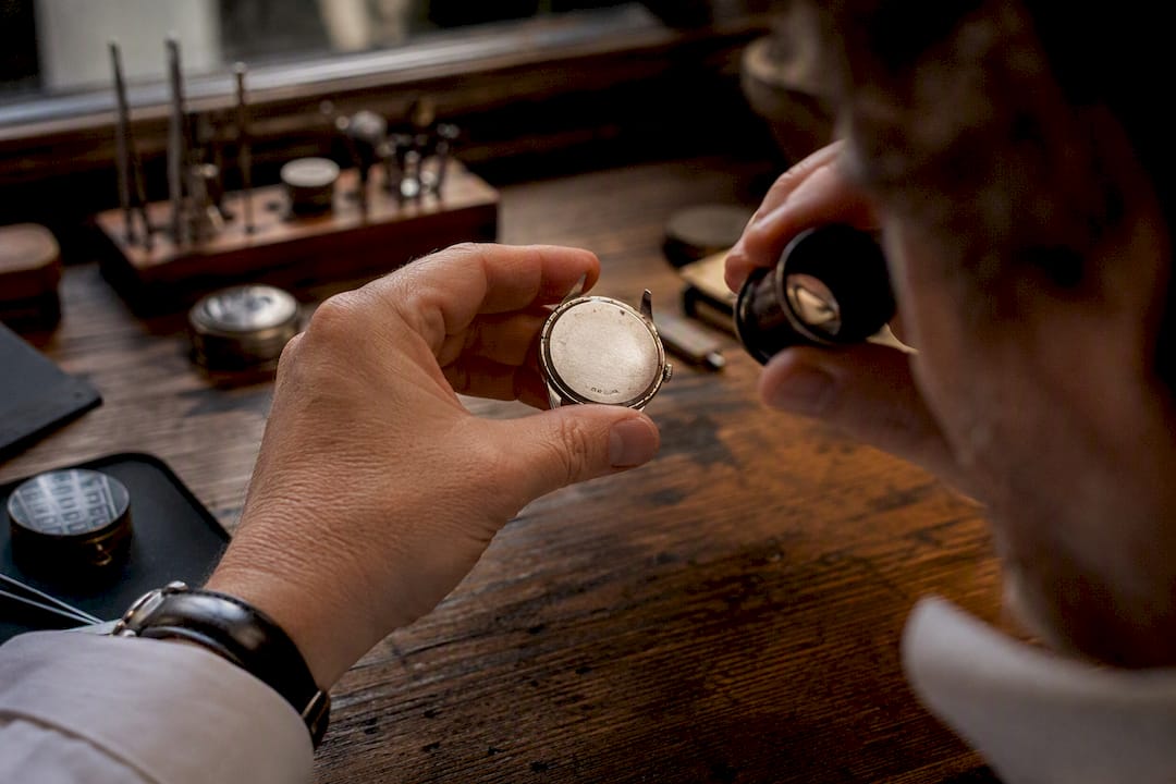 Watchmaker inspecting worn hallmark on watch case