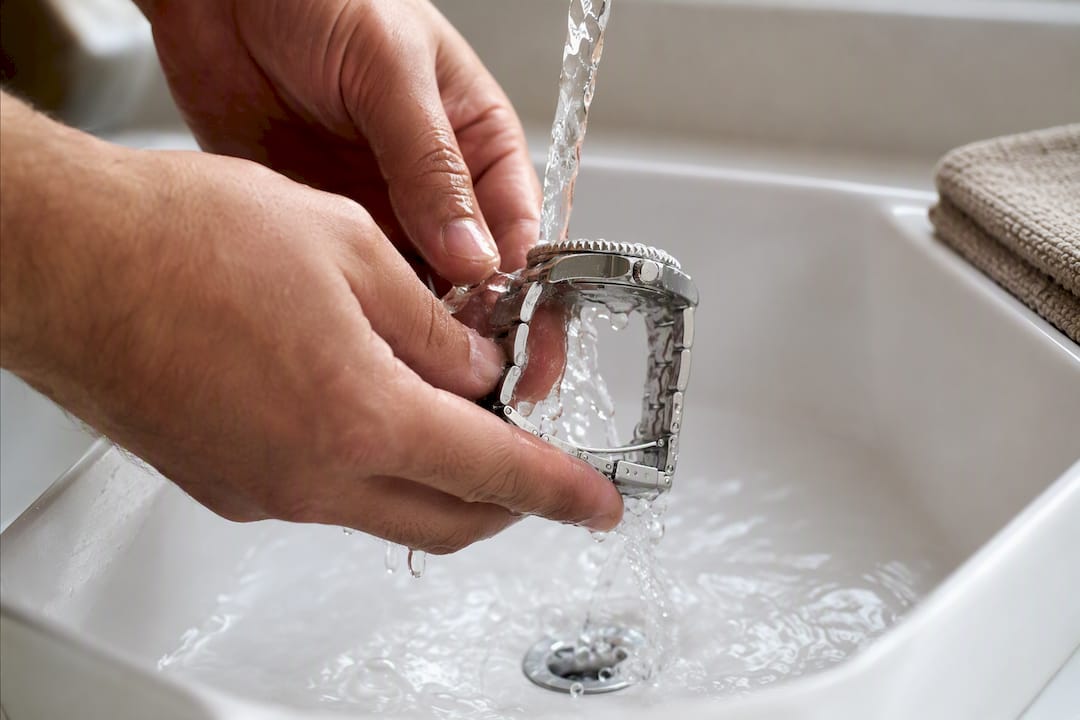 Hands rinsing a watch after water exposure