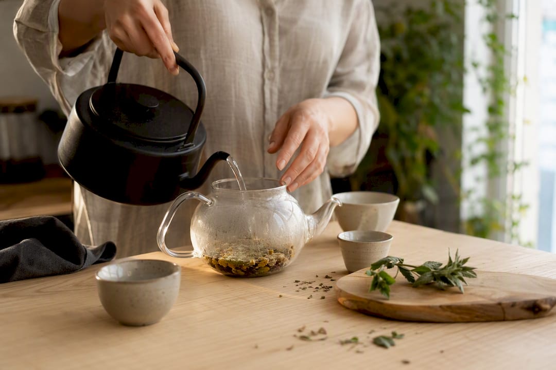 Mains versant de l'eau sur une infusion de plantes énergisante