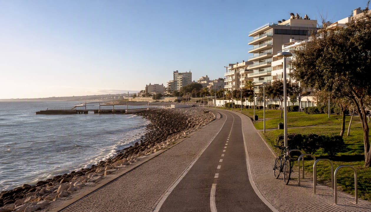 Zona costeira de Oeiras, onde o mar se cruza com edifícios modernos e urbanos.