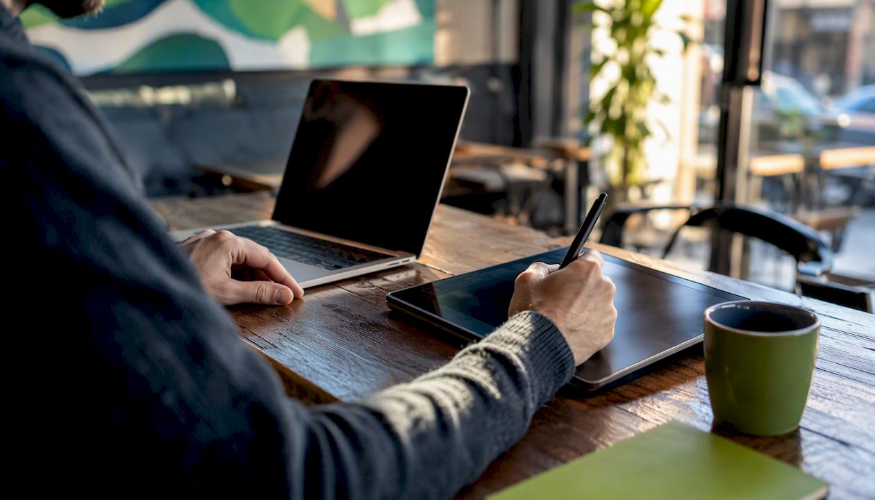 Hands jotting notes on tablet at outbound sales workspace