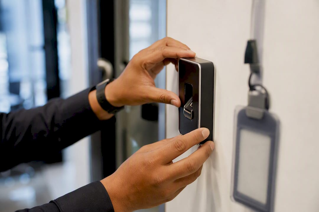 Mãos instalando um leitor biométrico de digitais