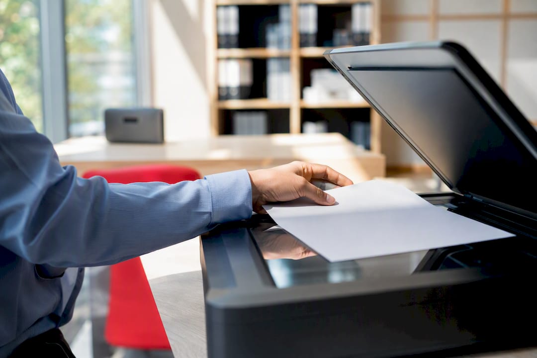 Mão colocando documento no scanner para digitalização