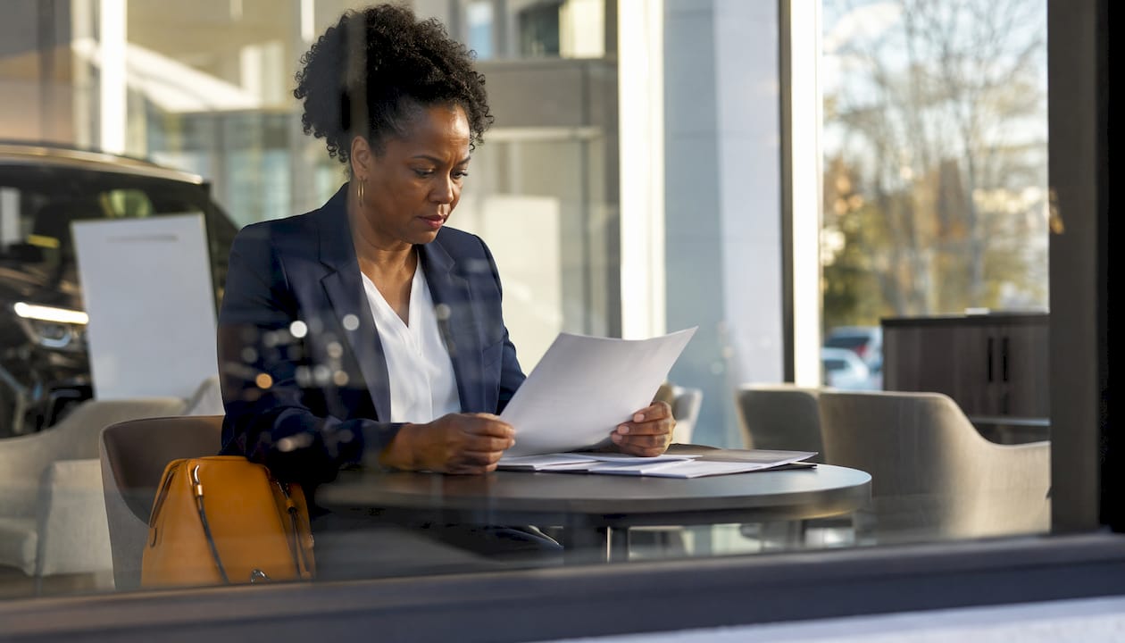 Woman reviewing car finance documents in dealership car