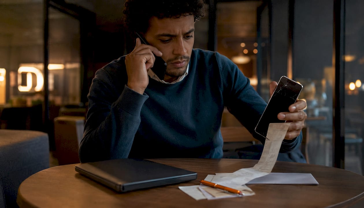 Ein Mann telefoniert mit dem Kundenservice und untersucht ein beschädigtes Produkt von Amazon.