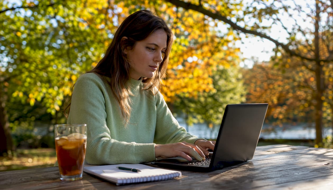 Jonge vrouw schrijft motivatiebrief voor chauffeursfunctie in een gezellig café.