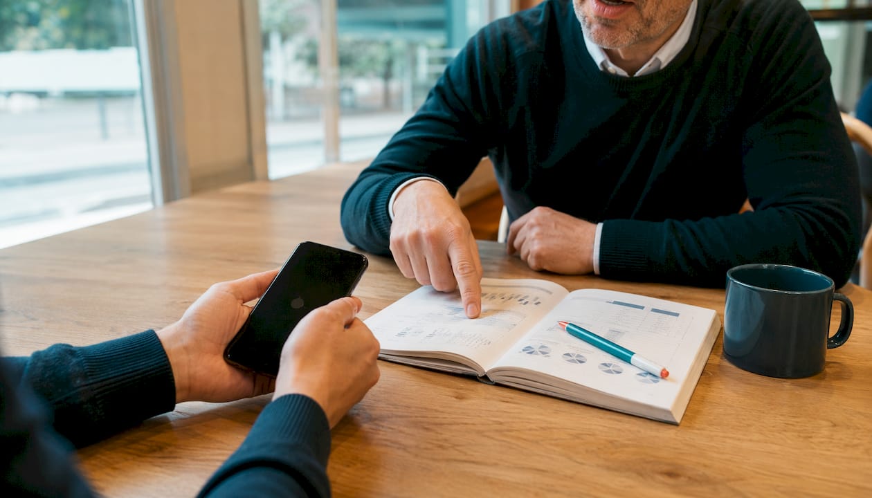 Een paar handen met een smartphone en aantekeningen, klaar om vacatures te zoeken op Indeed en LinkedIn.
