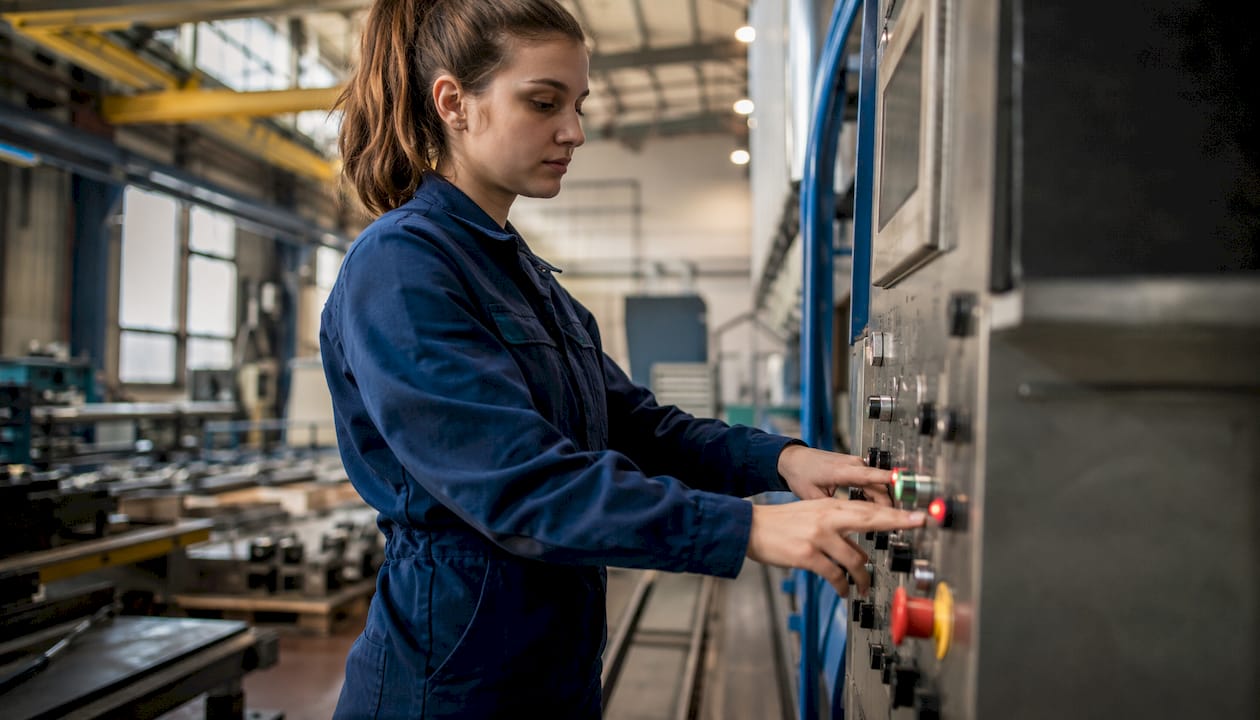 Een medewerker is op de werkvloer bezig met het bedienen van een industriële machine.