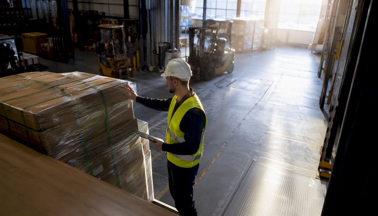 Een magazijnmedewerker controleert of de lading goed en veilig is vastgezet.