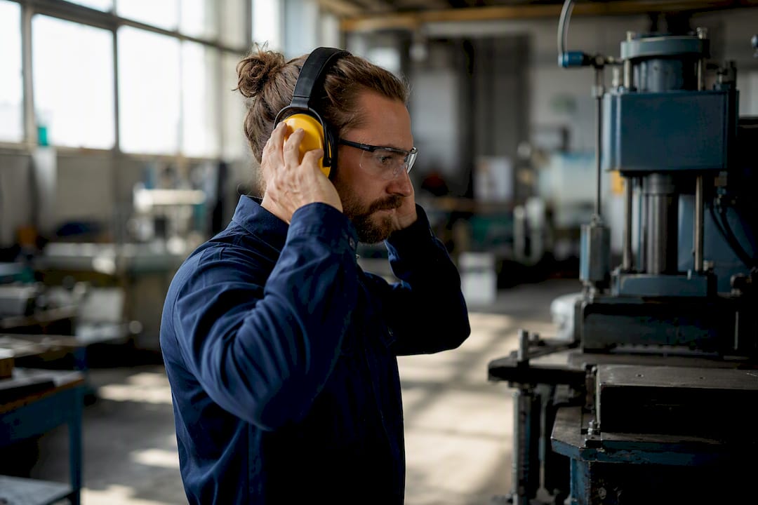 Medewerker met gehoorbeschermers op het werk