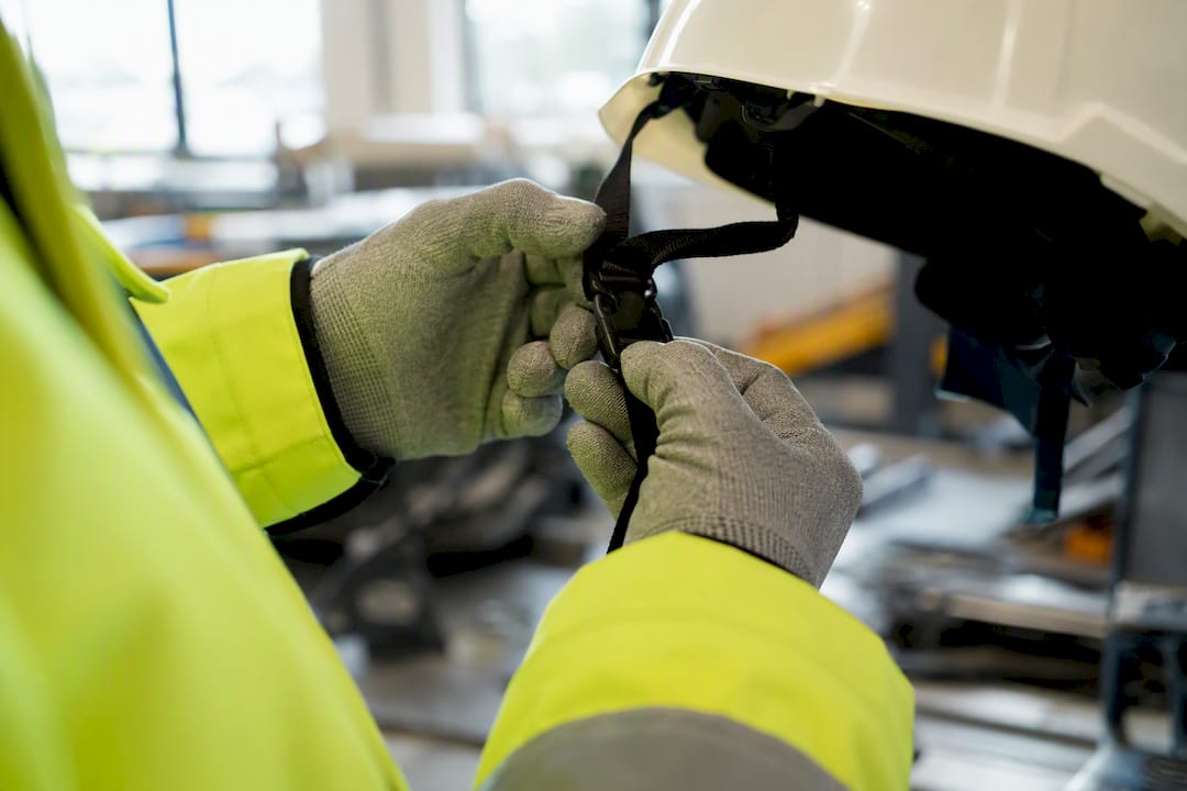Handen die het bandje van een veiligheidshelm vastmaken