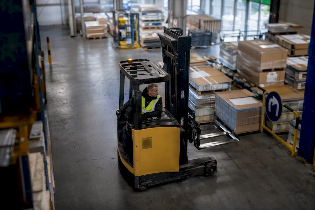 Reachtruckchauffeur rijdend in het magazijn