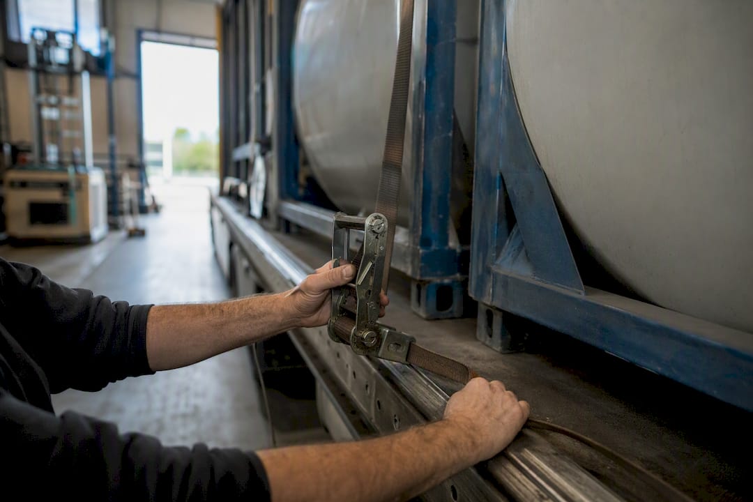 Chauffeur maakt lading vast met spanbanden op aanhanger