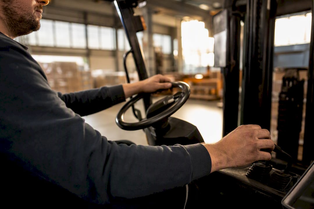Handen op de bediening van een heftruck in het magazijn